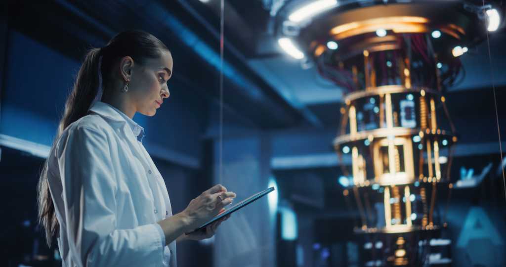 Female Engineer Working on Quantum Computer Hardware, Using Tablet Computer to Access Technical Specifications and Control Processor Parameters. Group of Developers Work on AI Behind a Desk